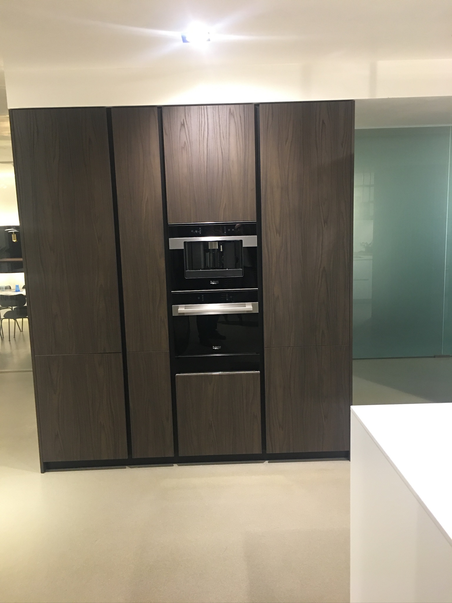 Tall timber-finish kitchen cupboards with an integrated coffee machine and ovens